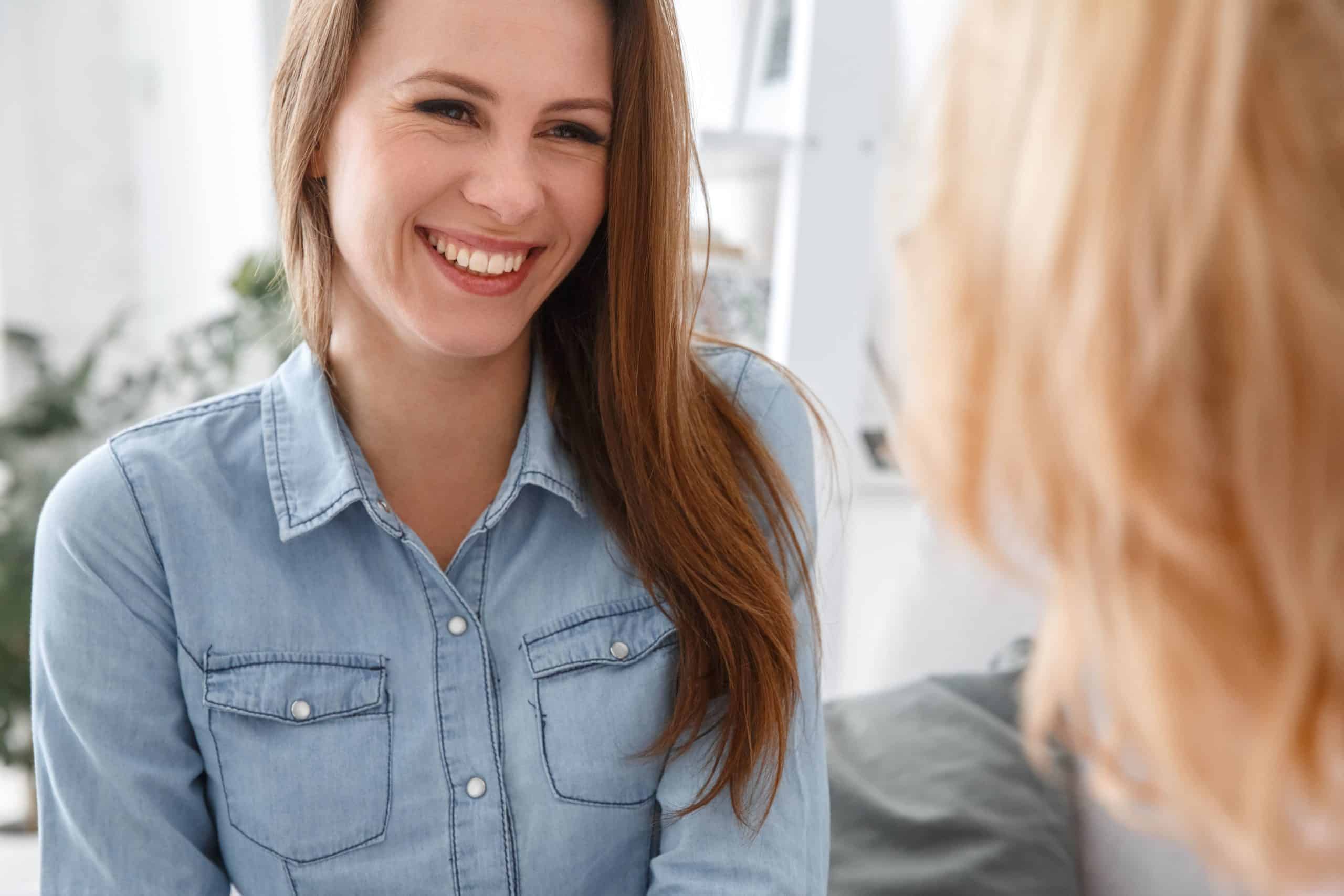 Woman smiling and looking at another woman who has her back turned